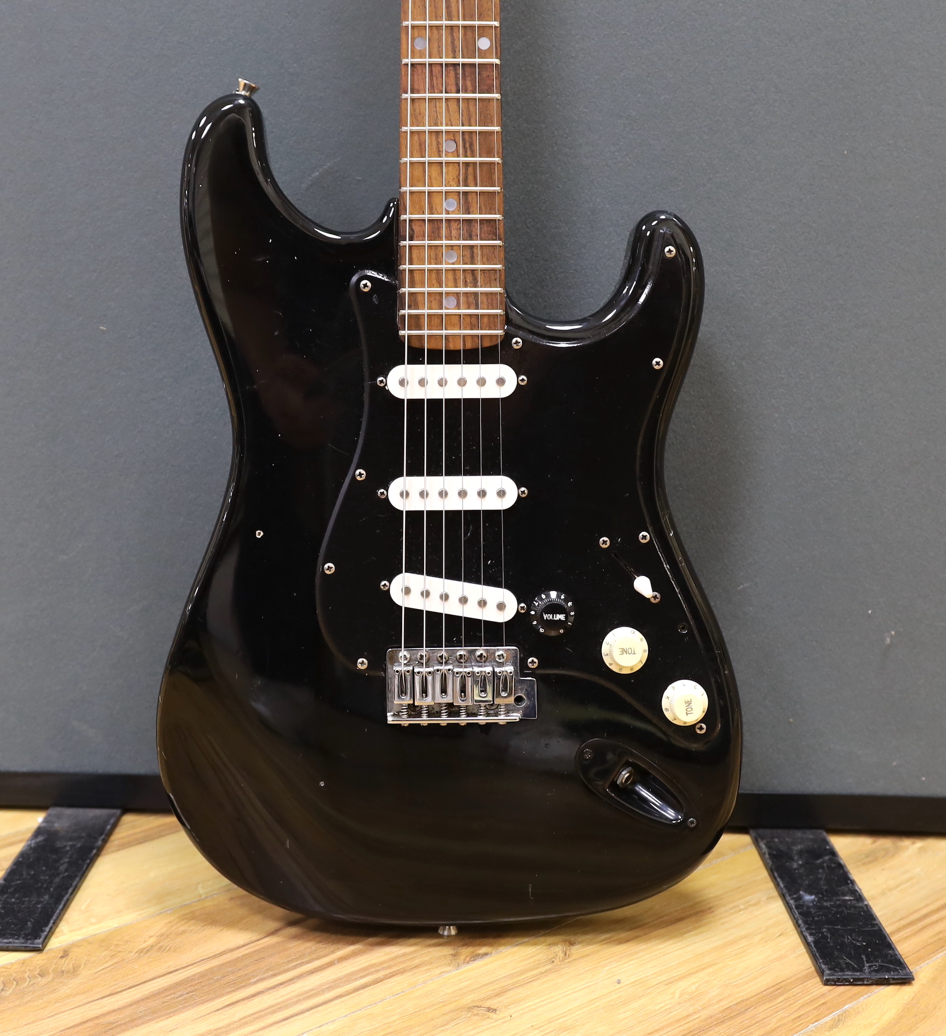 A cased Squier Strat by Fender electric guitar with rosewood neck and balance lacquer body, together with a Harris Tweed flight case